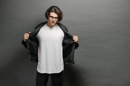 Hipster handsome male model with glasses wearing white blank t-shirt and black jeans with space for your logo or design in casual urban styleの写真素材