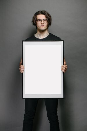 Man holding a picture frame or poster for mock up wearing black clothesの写真素材