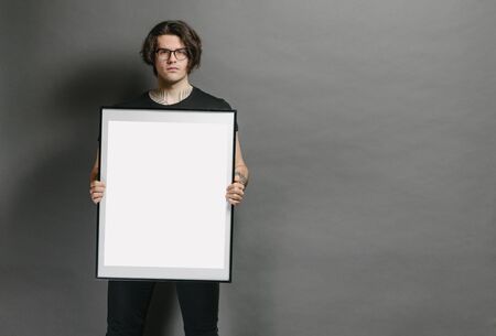 Man holding a picture frame or poster for mock up wearing black clothesの写真素材
