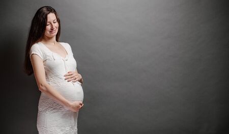 Pregnant woman portrait. She is holding a belly and smilingの写真素材