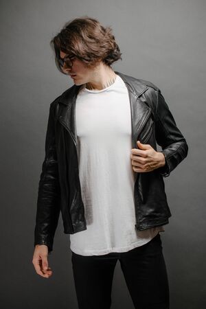 Hipster handsome male model with glasses wearing white blank t-shirt and black jeans with space for your logo or design in casual urban styleの写真素材