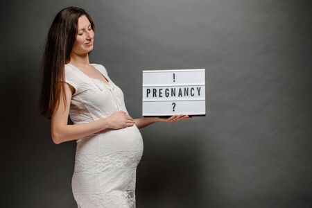 Pregnant woman portrait. She is holding a belly and smilingの写真素材