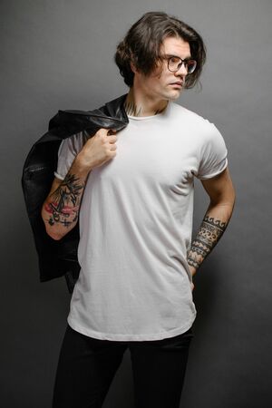 Hipster handsome male model with glasses wearing white blank t-shirt and black jeans with space for your design in casual urban styleの写真素材