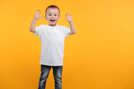 Kid boy wearing white t-shirt with space for your  design over yellow backgroundの写真素材