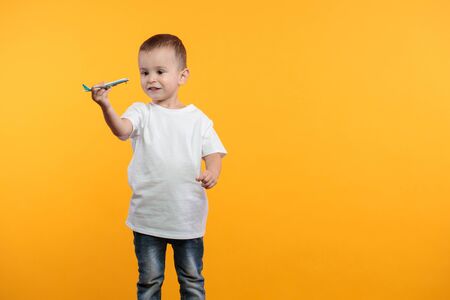 Kid boy wearing white t-shirt with space for your  design over yellow backgroundの写真素材