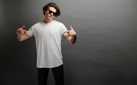 Hipster handsome male model with glasses wearing white blank t-shirt and black jeans with spaceの写真素材