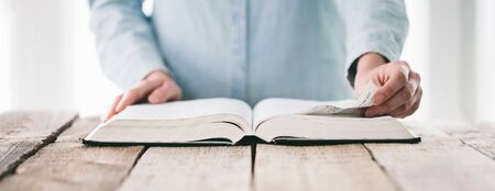 Hands turning the page of a bible Hands turning the page of a bible. Woman reading a big book or a Bibleの写真素材