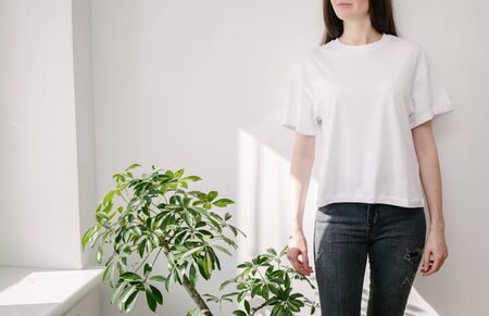 Skinny woman wearing white blank t-shirt and black jeans with space for your logo or design in casual urban style over white wallの写真素材