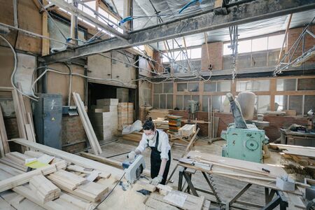Confident woman working as carpenter in her own woodshop. Carpentry interior