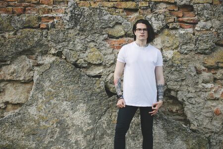 Hipster handsome male model wearing white blank t-shirt with space for your logo or design in casual urban styleの写真素材