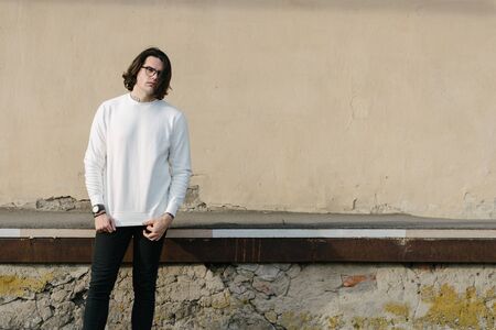 Man wearing white sweatshirt or hoodie and glasses outside on the city streets. Sweatshirt or hoodie for mock up, logo designs or design prints with free space.の写真素材