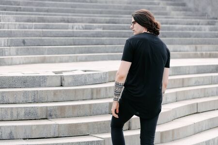 Handsome male model with beard wearing black blank t-shirt with free space for your logo or design in casual urban styleの写真素材