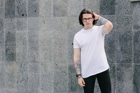 Hipster handsome male model wearing white blank t-shirt with space for your logo or design in casual urban styleの写真素材