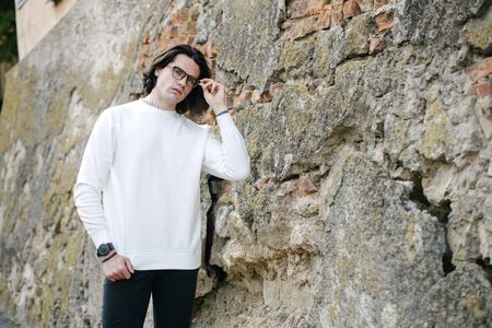 Man wearing white sweatshirt or hoodie and glasses outside on the city streets. Sweatshirt or hoodie for mock up, logo designs or design prints with free space.の写真素材