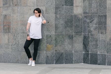Hipster handsome male model wearing white blank t-shirt with space for your logo or design in casual urban styleの写真素材