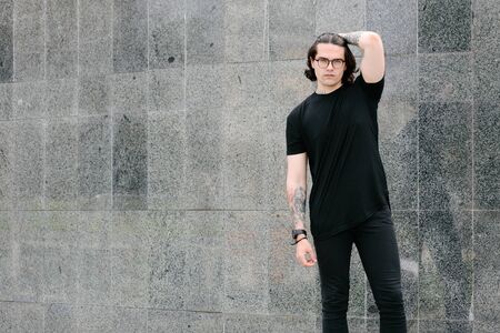 Handsome male model with beard wearing black blank t-shirt with free space for your logo or design in casual urban styleの写真素材