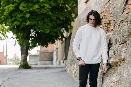 Man wearing white sweatshirt or hoodie and glasses outside on the city streets. Sweatshirt or hoodie for mock up, logo designs or design prints with free space.の写真素材