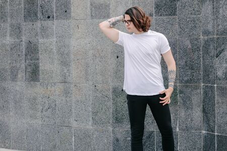 Hipster handsome male model wearing white blank t-shirt with space for your logo or design in casual urban styleの写真素材