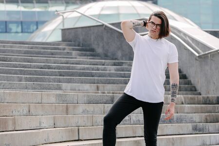 Hipster handsome male model wearing white blank t-shirt with space for your logo or design in casual urban styleの写真素材