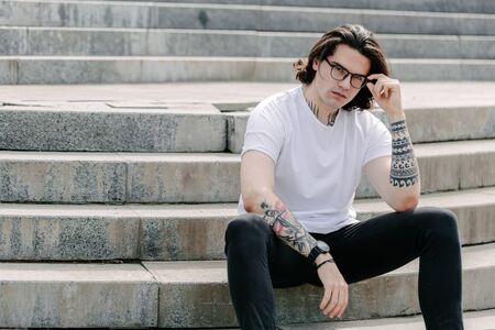 Hipster handsome male model wearing white blank t-shirt with space for your logo or design in casual urban styleの写真素材
