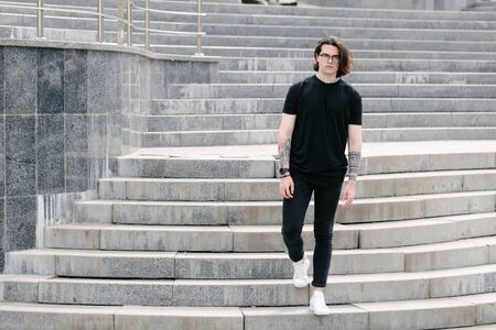 Handsome male model with beard wearing black blank t-shirt with free space for your logo or design in casual urban styleの写真素材