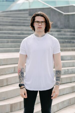 Hipster handsome male model wearing white blank t-shirt with space for your logo or design in casual urban styleの写真素材