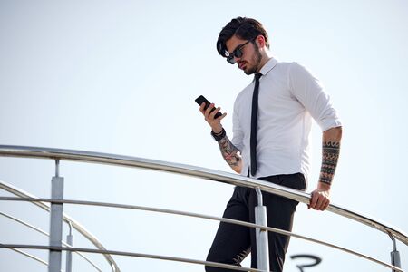 Handsome businessman making a phone call or using a phone outsideの写真素材