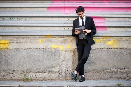 Young Businessman using a tablet pc outside wearing a classic suitの写真素材