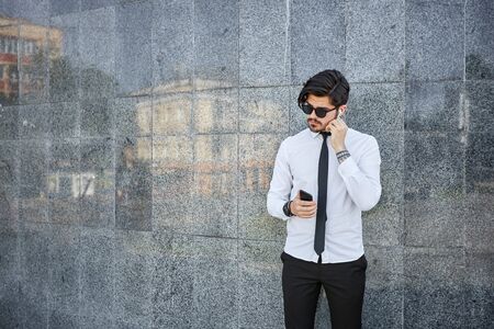 Handsome businessman making a phone call or using a phone outsideの写真素材