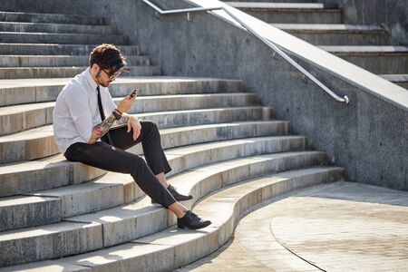 Handsome businessman making a phone call or using a phone outsideの写真素材