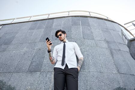 Handsome businessman making a phone call or using a phone outsideの写真素材