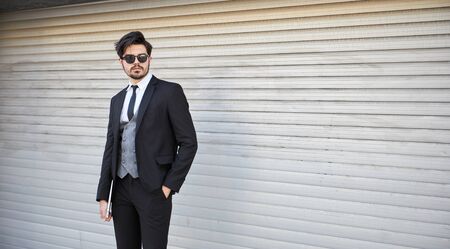 Portrait of a young businessman in a suit outdoor holding a laptopの写真素材