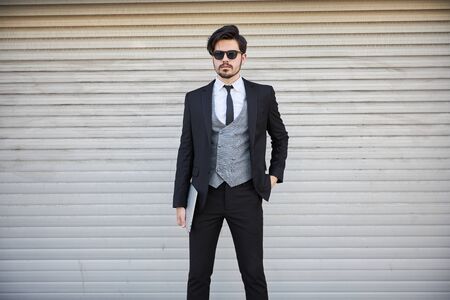 Portrait of a young businessman in a suit outdoor holding a laptopの写真素材