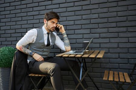 Handsome businessman making a phone call or using a phone outsideの写真素材