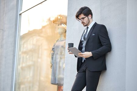 Young Businessman using a tablet pc outside wearing a classic suitの写真素材