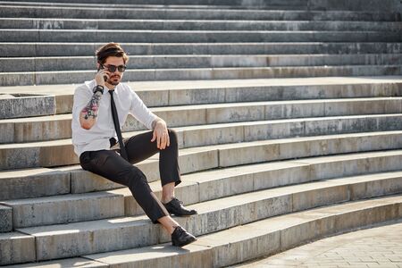 Handsome businessman making a phone call or using a phone outsideの写真素材