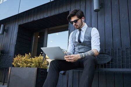 Young handsome man sitting and working on laptopの写真素材