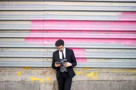 Young Businessman using a tablet pc outside wearing a classic suitの写真素材