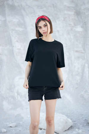 Sexy woman or girl wearing black blank t-shirt with space for your logo, mock up or design outdoorsの写真素材
