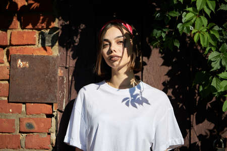 Sexy brunette woman with a make up wearing white clothes outside with tree shadows on a faceの写真素材