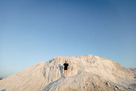 Slim beautiful girl at sunset over white mountain looking at the sun in the summerの写真素材