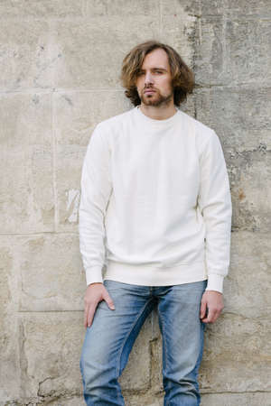 Man wearing white sweatshirt or hoodie for mock up, logo designs or design prints with with free space among europe city streets.の写真素材