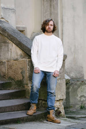 Man wearing white sweatshirt or hoodie for mock up, logo designs or design prints with with free space among europe city streets.の写真素材