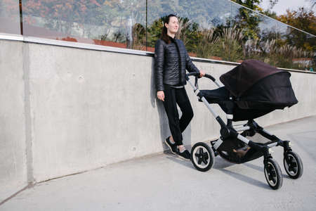 Mother with a pram or stroller on modern city streets walking and relaxing in autumnの写真素材