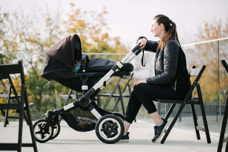 Mother with a pram or stroller on modern city streets walking and relaxing in autumnの写真素材