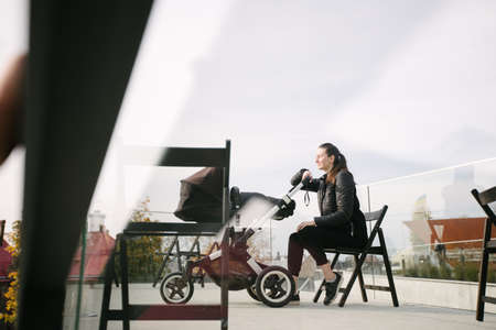 Mother with a pram or stroller on modern city streets walking and relaxing in autumnの写真素材