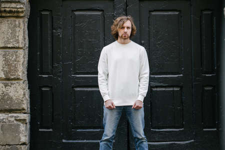 Man wearing white sweatshirt or hoodie for mock up, logo designs or design prints with with free space among europe city streets.の写真素材