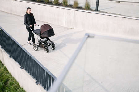 Mother with a pram or stroller on modern city streets walking and relaxing in autumnの写真素材