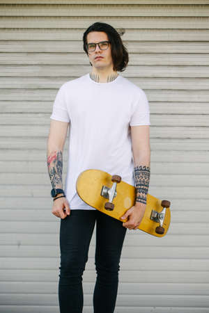 Hipster handsome male model with glasses wearing white blank t-shirt and black jeans with space for your   or design in casual urban styleの写真素材
