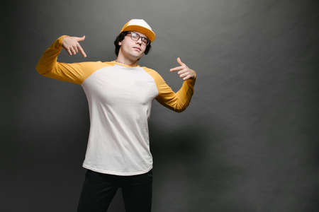 Man model with beard wearing white and yellow blank Long Sleeve Shirt for mock up and a baseball cap with space for your   design over gray backgroundの写真素材